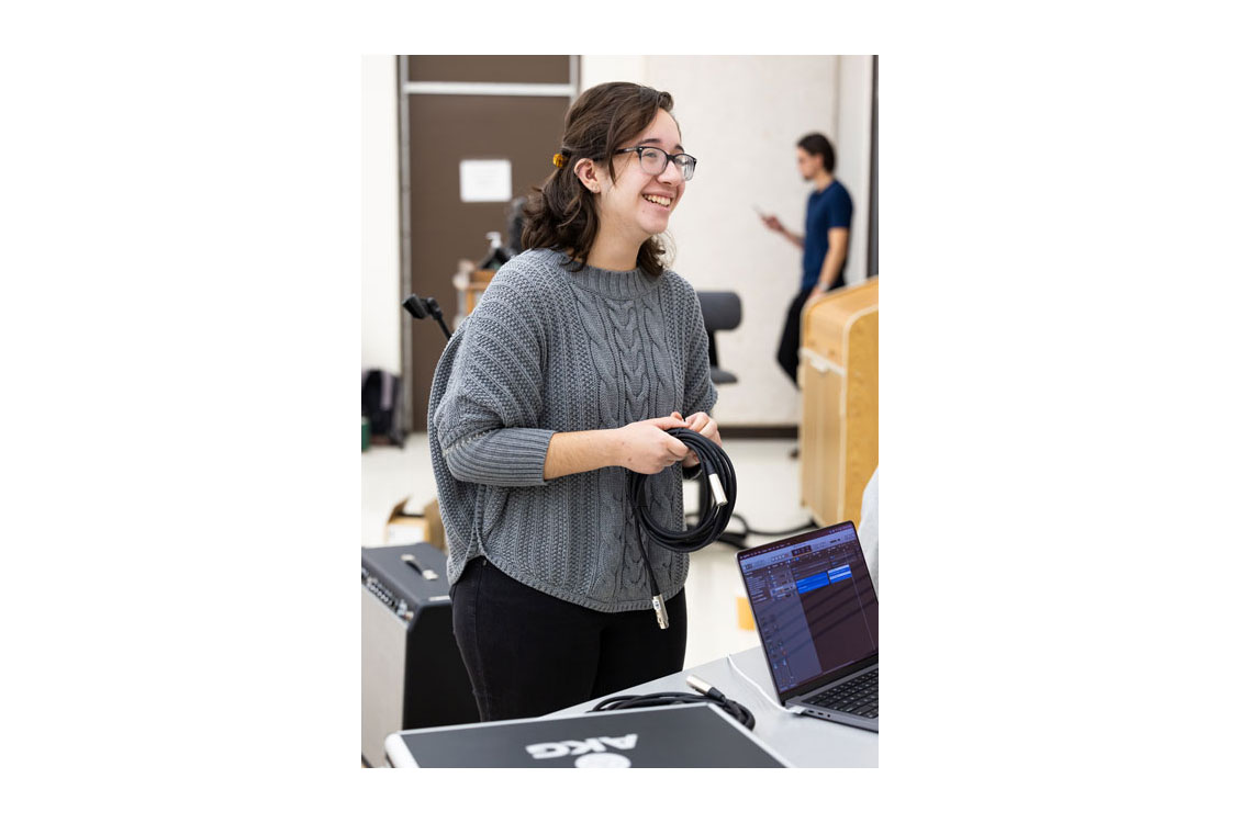 A student smiles while wrapping up audio cables