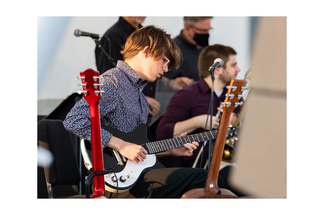 a student plays the guitar at an outdoor concert